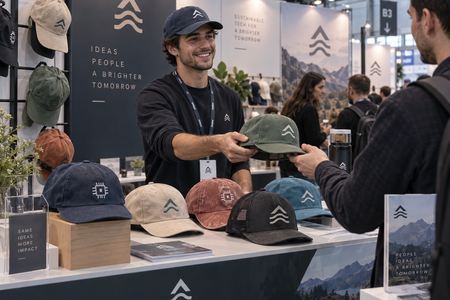 Custom baseball caps being handed out at a trade show stand