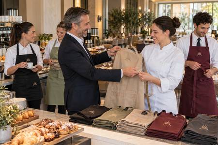 Hotel staff receiving personalised aprons decorated with a coordinated symbol.