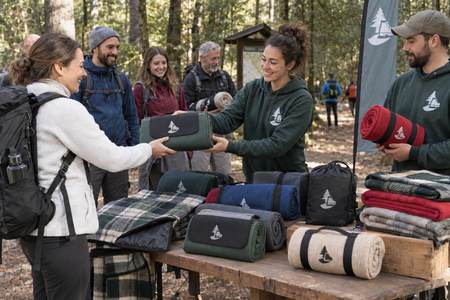 Hiking association volunteers handing out personalised camping blankets to woodland walkers